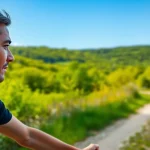 Experience the innovation of F1 Bone Conduction Headphones worn by a cyclist on a scenic trail.